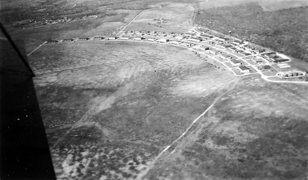 An aerial photograph of Brooks Field in Texas, showcasing the massive crescent-shaped layout of military hangars and barracks.