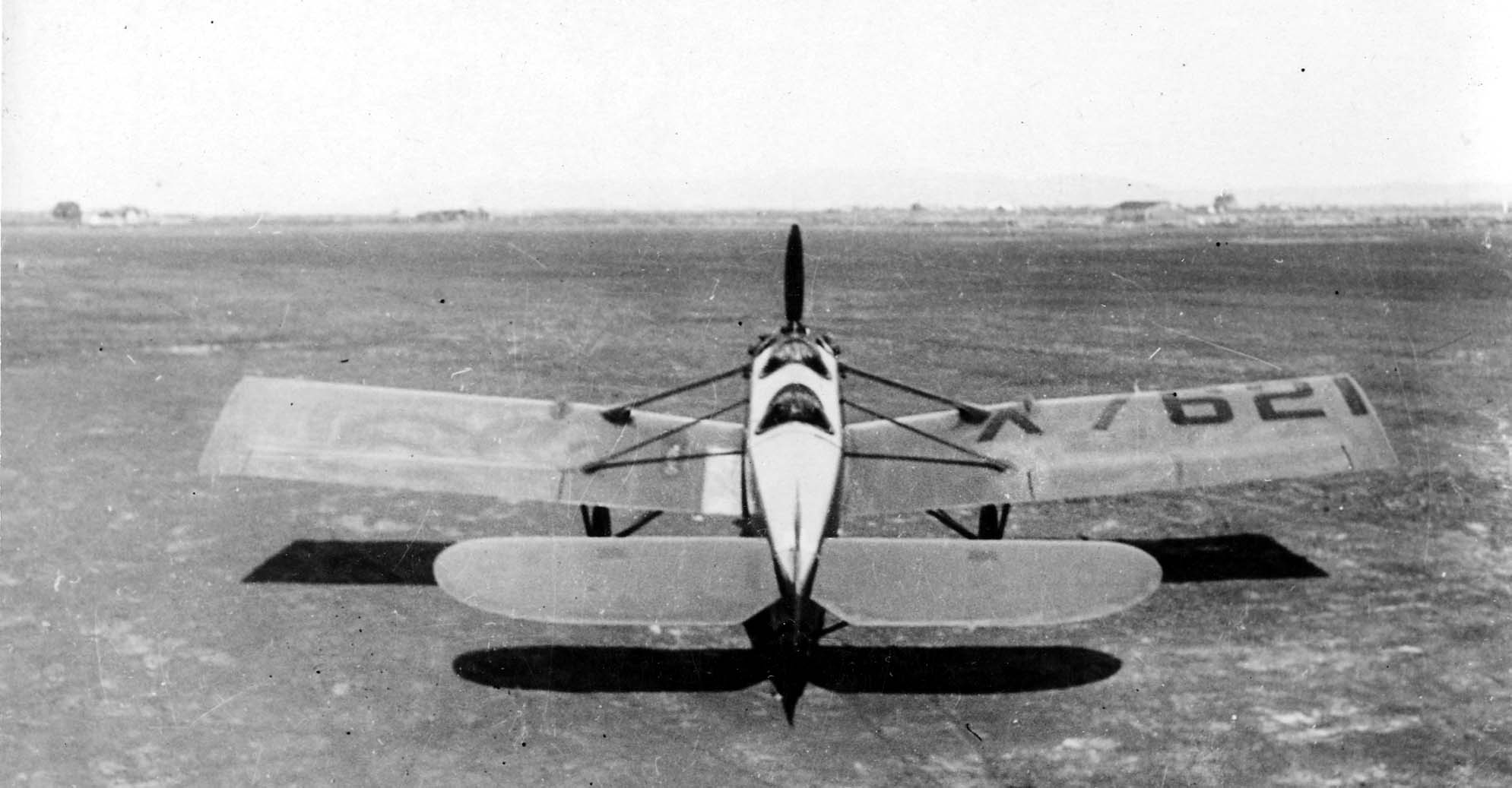 A direct centerline rear-to-front perspective of the Hall X-1 prototype X7621 on an open airfield, detailing the large aft-wing stabilator.