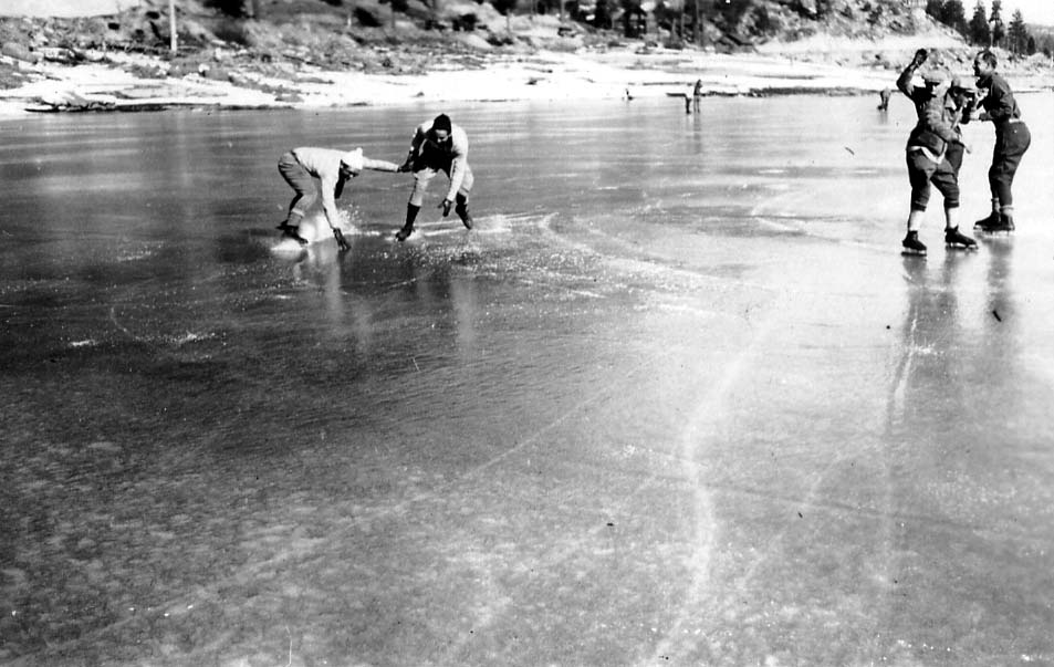 Three men intensely racing or playing a game on a frozen lake, leaning hard into a sharp turn and throwing up ice spray.
