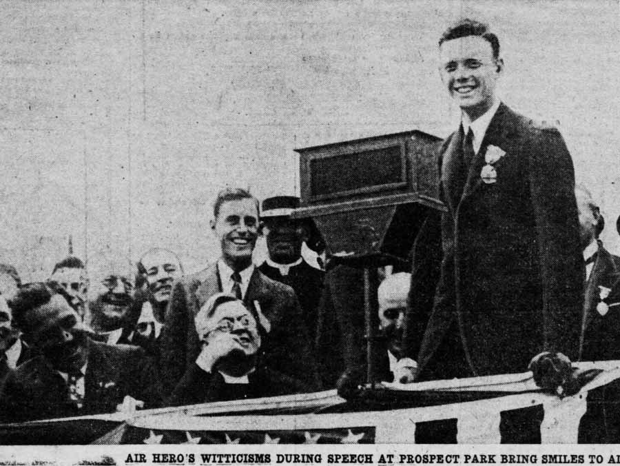 A newspaper clipping showing Charles Lindbergh smiling and speaking at a podium in Prospect Park, Brooklyn.