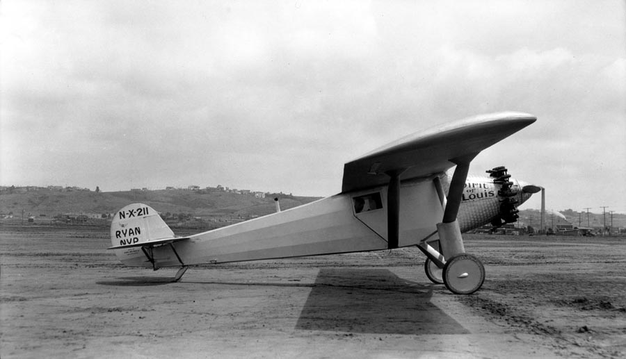 A side profile of the Spirit of St. Louis parked on the dirt at Dutch Flats, with the silhouette of Charles Lindbergh visible inside the cockpit preparing for takeoff.