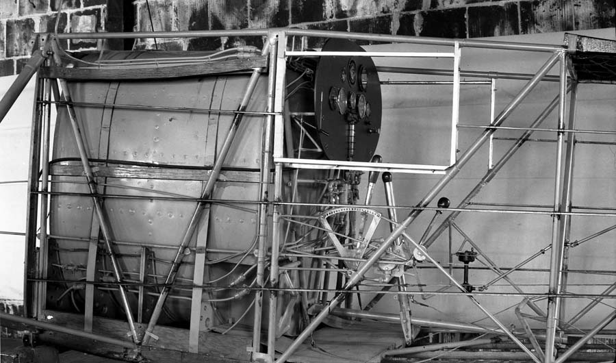 The bare tubular steel framework of the Spirit of St. Louis cockpit, showing the instrument panel mounted directly in front of the massive main fuel tank.