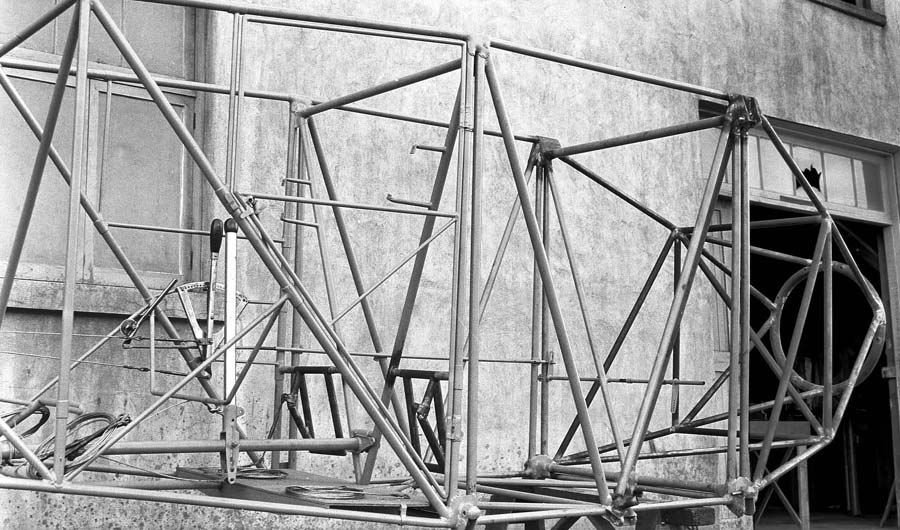 A detailed view of the forward section of the raw tubular steel fuselage framework, showing the engine mount ring and cockpit controls.