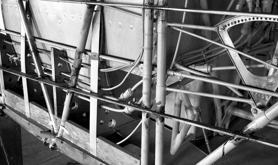 A close-up detailed view of the custom fuel lines, connections, and valves routing around the main fuel tank of the Spirit of St. Louis.
