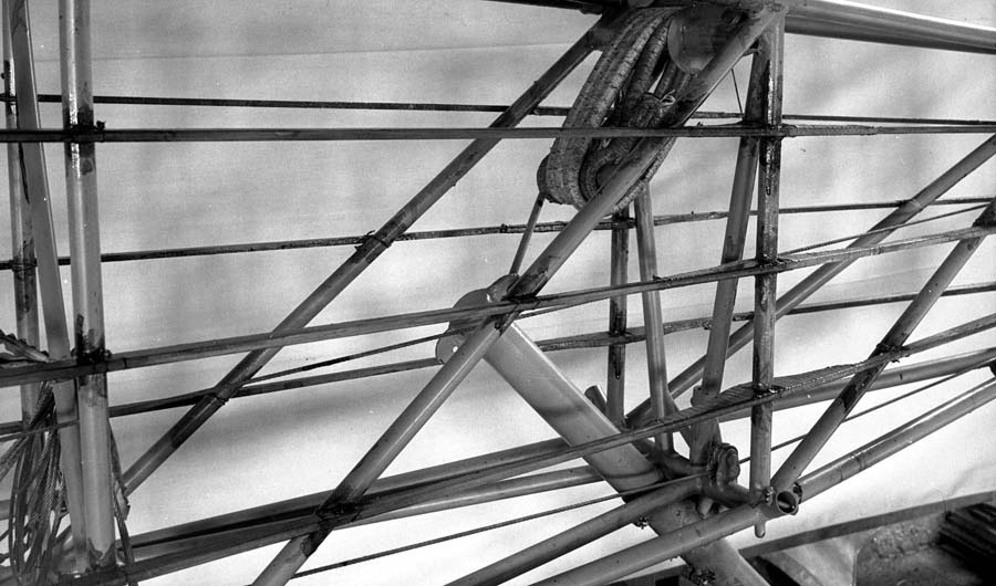 A detailed view of the tubular steel tail section of the Spirit of St. Louis, focusing on the complex wrapping of the bungee cord shock absorbers.