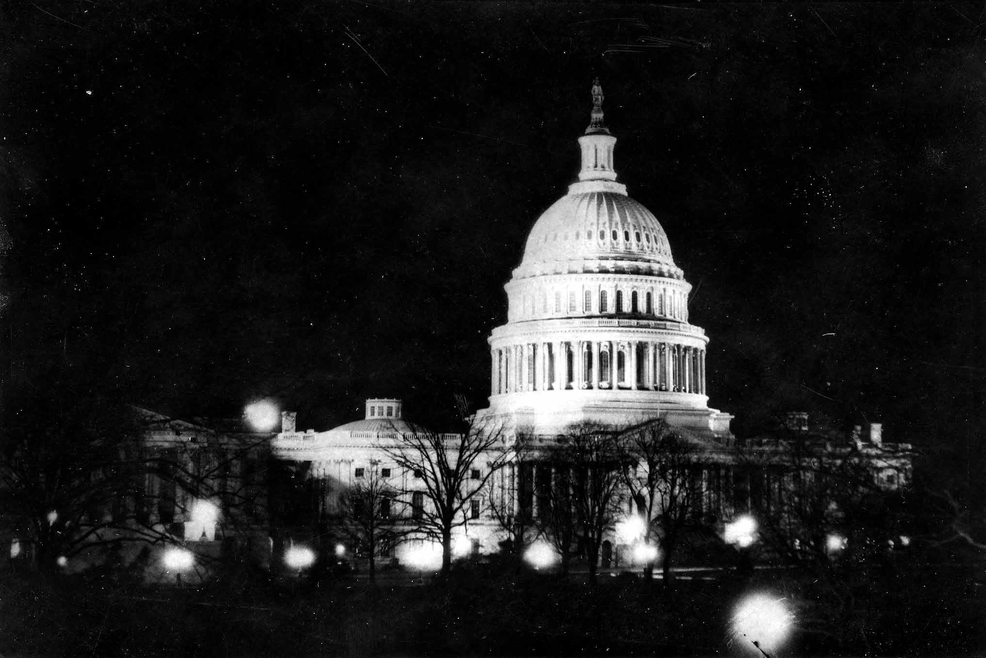 A striking night photograph of the United States Capitol building in Washington D.C., with its dome brightly illuminated against the dark sky.