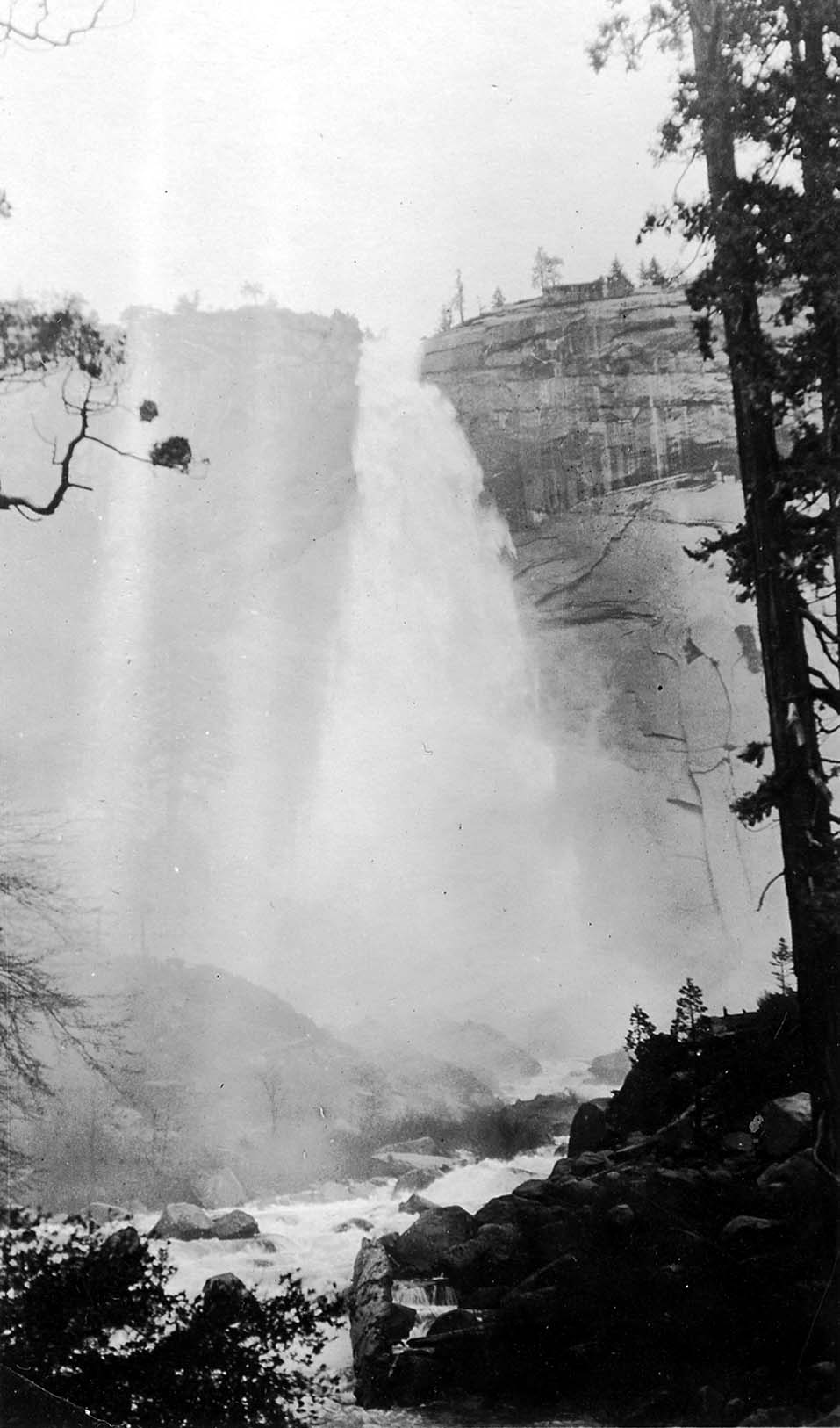 Looking up from the boulder-strewn bed of the Merced River at the powerful vertical cataract of Vernal Fall shrouded in mist.
