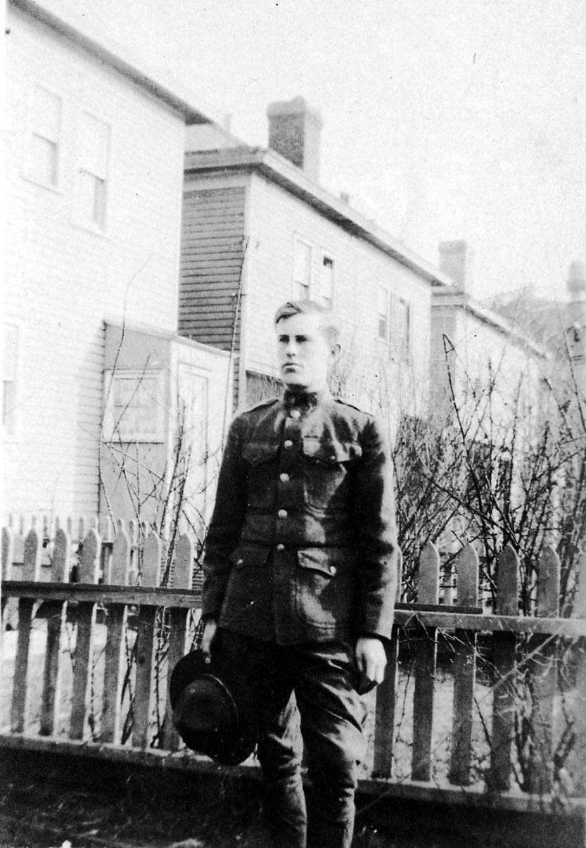 Young Donald A. Hall in U.S. Army World War I uniform holding service cap outside Brooklyn home.