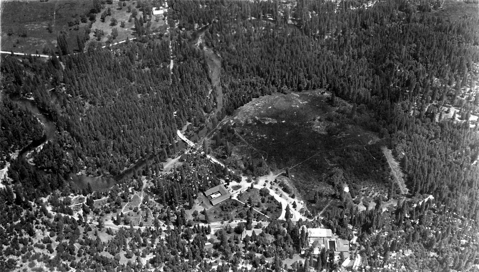 A vertical bird's-eye overlook looking straight down from Glacier Point at Stoneman Meadow, the winding Merced River, and Camp Curry.
