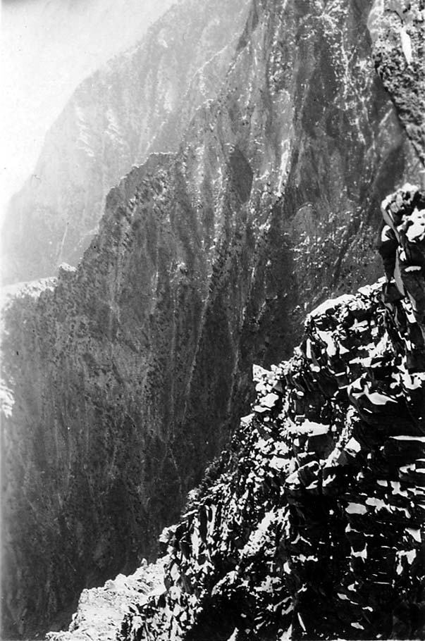 A steep, rocky mountain cliff face bathed in natural sunlight.