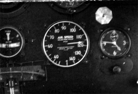 Macro photograph of cockpit instrument cluster during high-speed test run showing airspeed indicator needle at 120 mph.