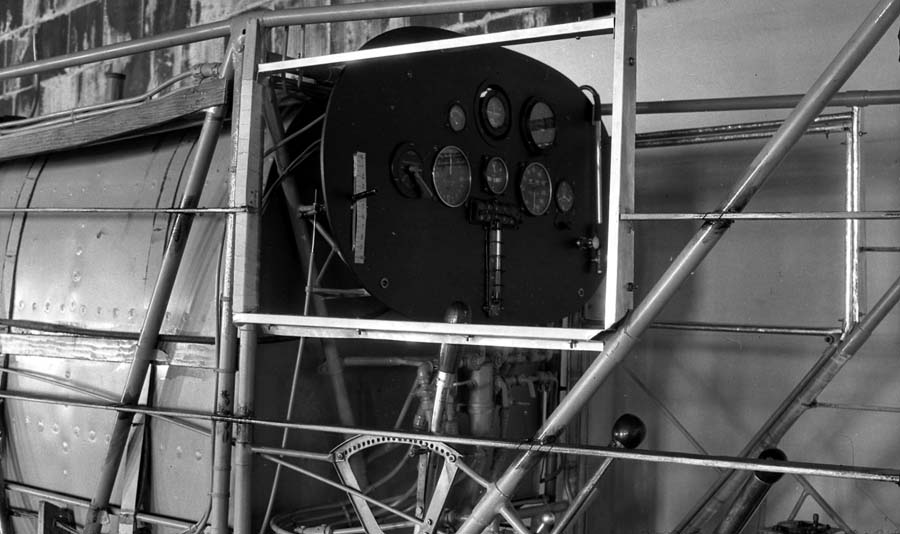 Workshop photograph of uncovered fuselage frame showing instrument panel mounted behind main fuel tank.