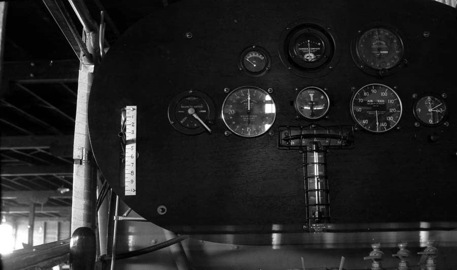 Close-up view of the black oval instrument panel showing compass, airspeed, tachometer, and calibrated starter lever.
