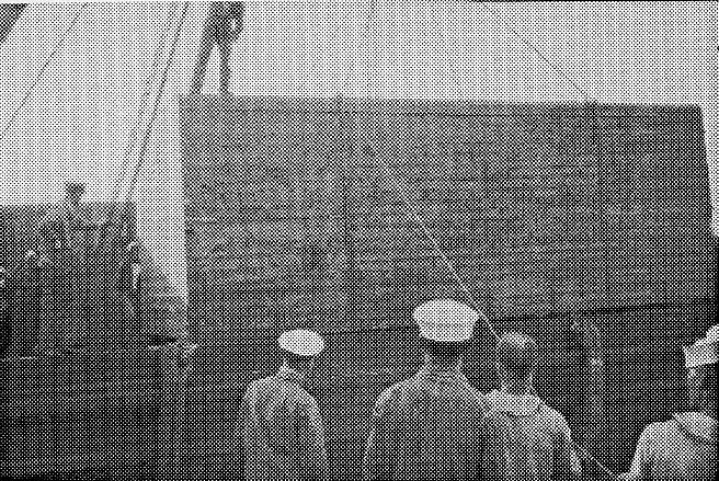 Large wooden crate containing the disassembled Spirit of St. Louis being hoisted off the USS Memphis with sailors watching.