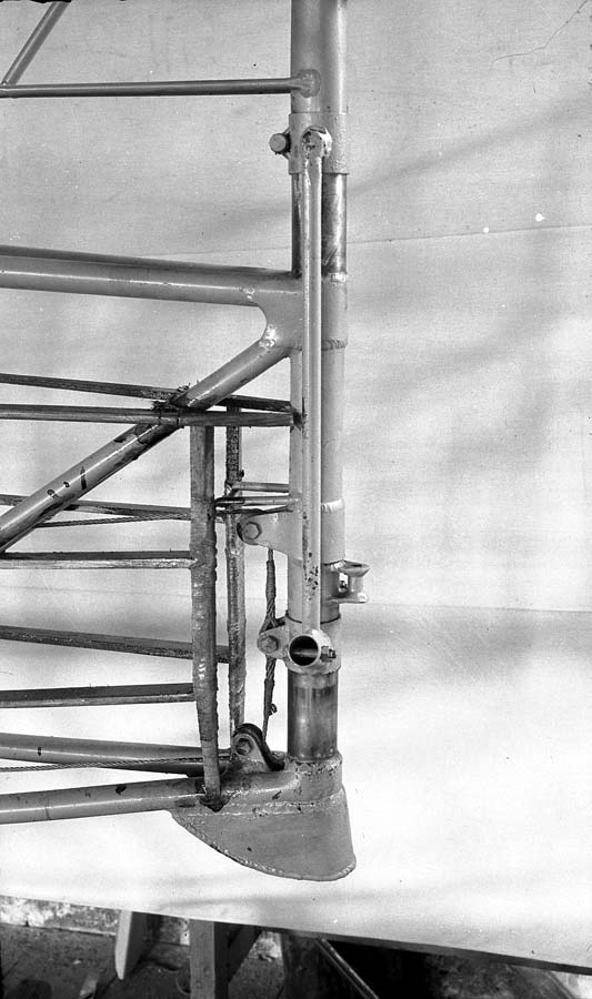 Macro engineering view of bare steel-tube tailpost, rudder hinge fittings, and reinforced tail skid jack point.