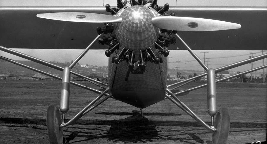 Head-on close-up photograph of the Spirit of St. Louis nose showing damascened cowl, spinner, engine, and gear struts.