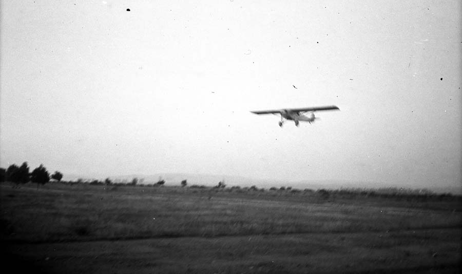 Airborne photograph of the Spirit of St. Louis banking low over the terrain during Camp Kearny flight trials.