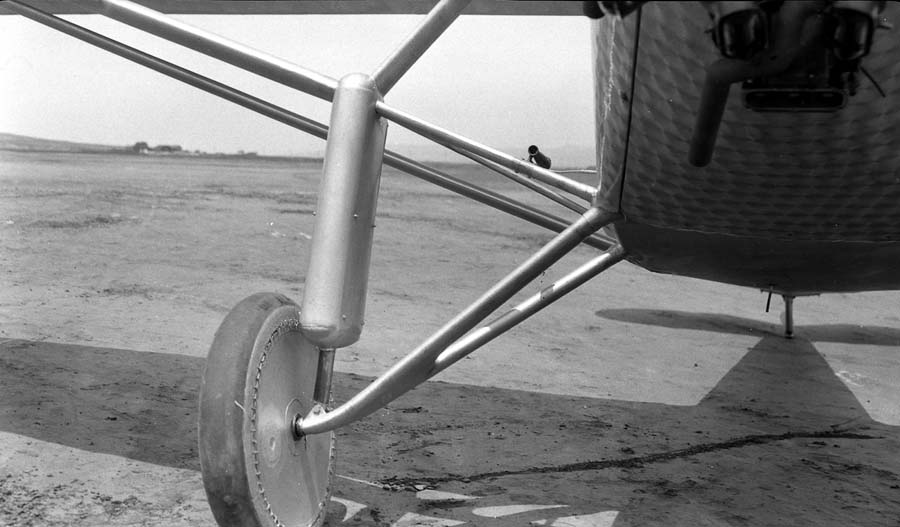 Low ground-level view of the right split-axle landing gear, bungee shock fairing boot, and fabric wheel cover.