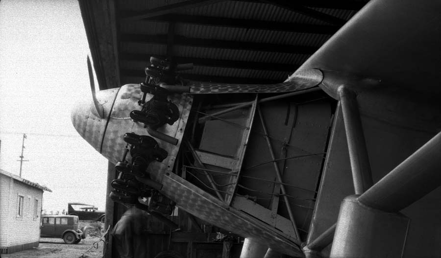 Close-up under hangar roof of the uncowled Wright Whirlwind engine, fuselage mount, and propeller.